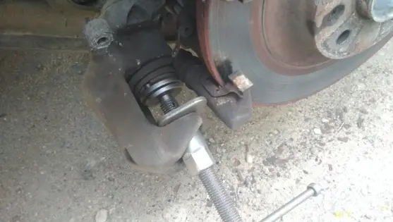 Вдавлювання поршня гальмівного супорта струбциною під час заміни колодок