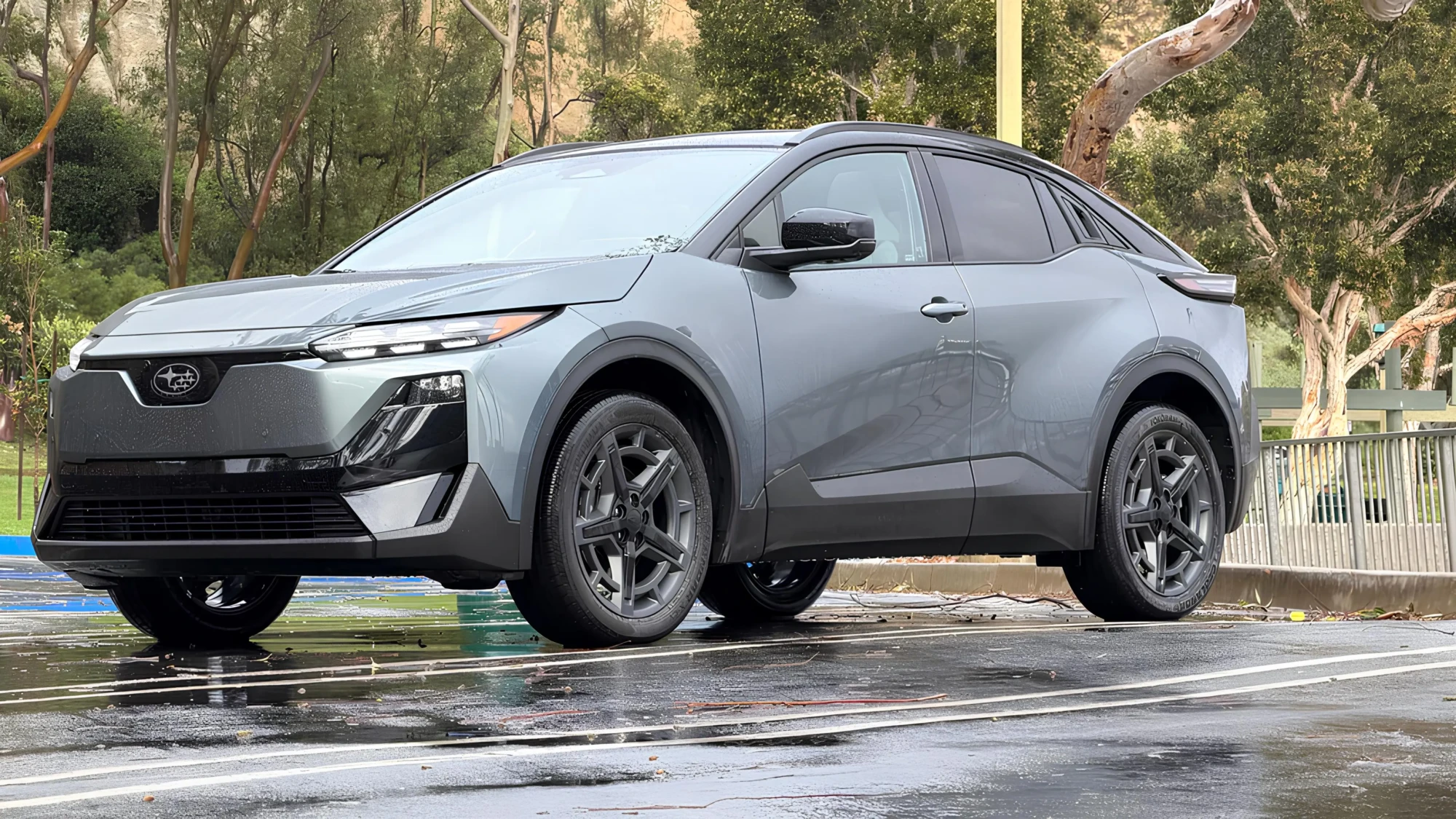 Сірий електричний кросовер Subaru у міському паркуванні після дощу, вигляд спереду збоку