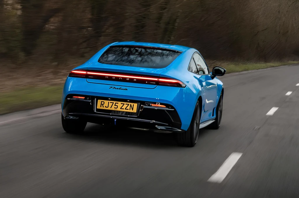 Синее купе Honda в движении по дороге, вид спереди сбоку