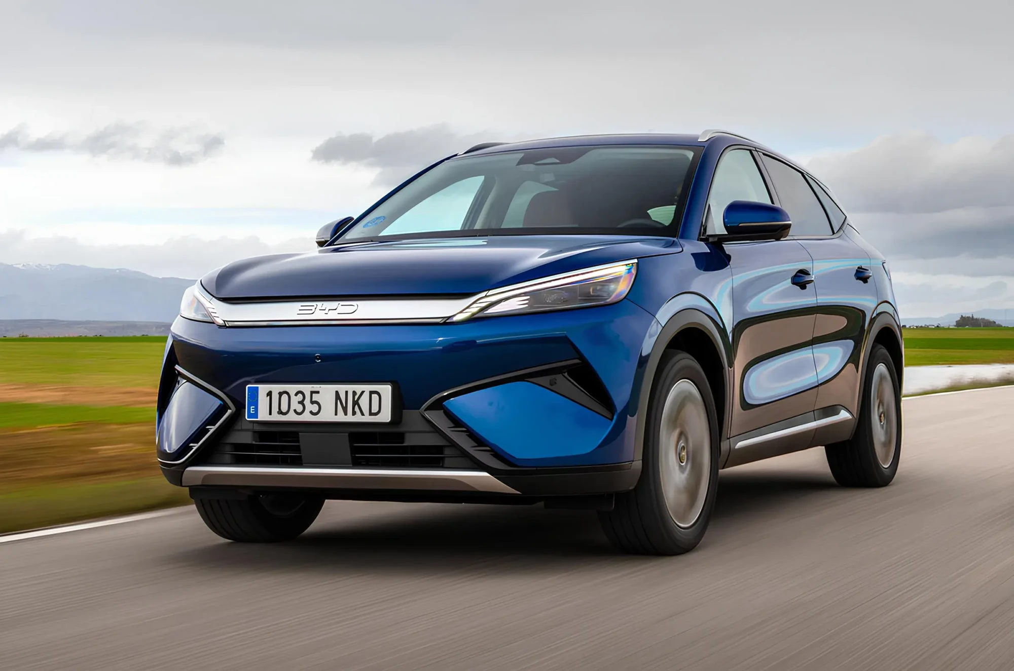 Синій електричний кросовер BYD Atto 3 у русі дорогою, вигляд спереду збоку