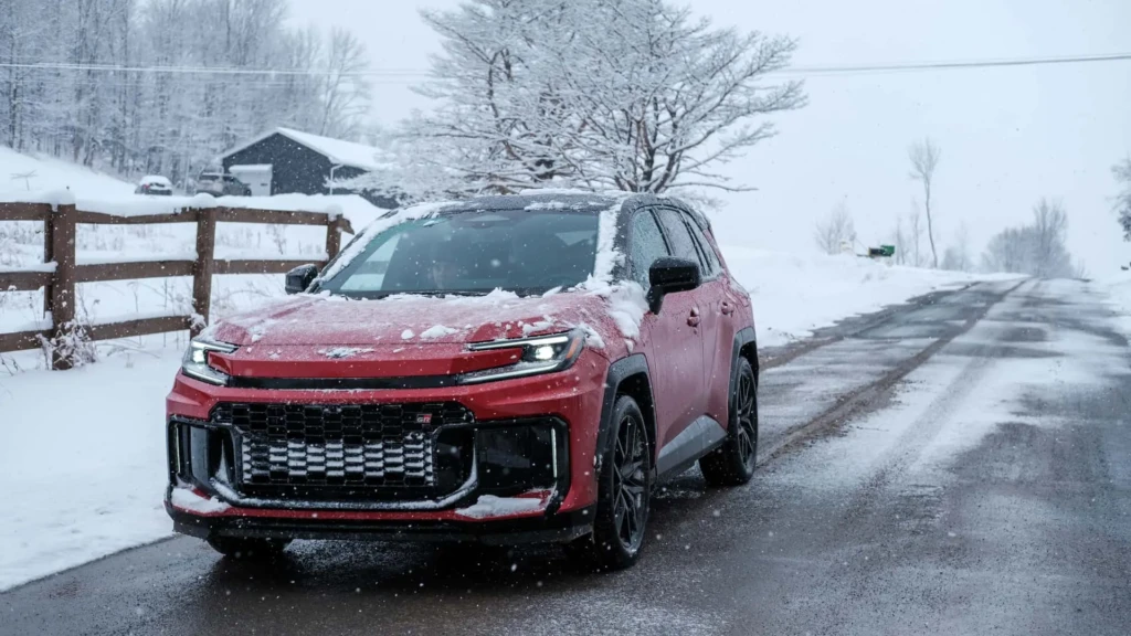 Красный Toyota RAV4 на зимней дороге: кроссовер со снегом на кузове, вид спереди под углом