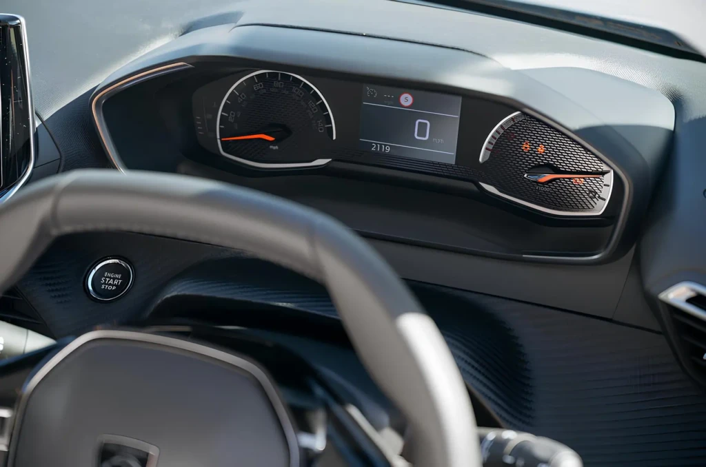Панель приладів автомобіля Peugeot: аналоговий спідометр, цифровий дисплей зі швидкістю 0 км/год і кнопка Start/Stop на торпедо.