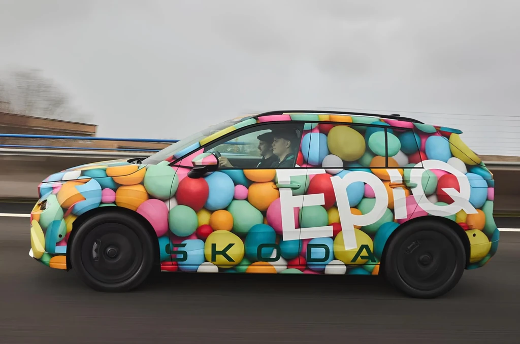 Прототип кроссовера Škoda в ярком камуфляже «шарики», вид сбоку в движении по трассе