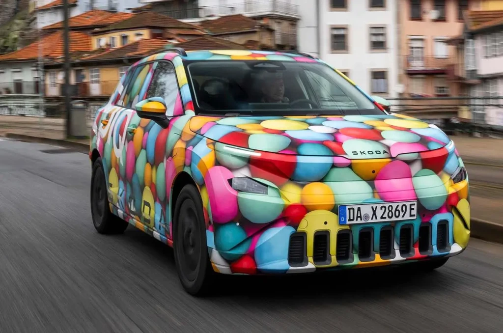 Прототип кросовера Škoda в яскравому камуфляжі «кульки», передній ракурс у русі міською вулицею