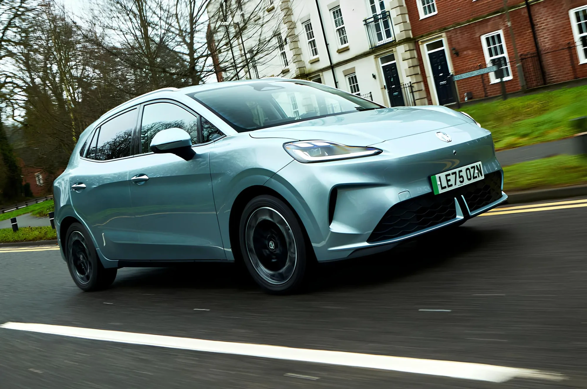 Електромобіль MG4 у русі: світло-блакитний хетчбек їде міською вулицею, вигляд спереду під кутом