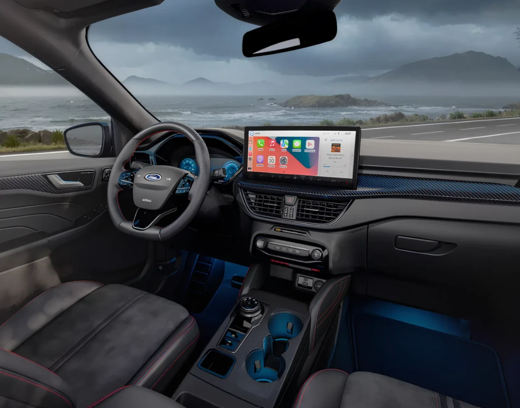 Інтер’єр авто Ford з великим центральним екраном. За вікном — море, скелі й похмуре небо.