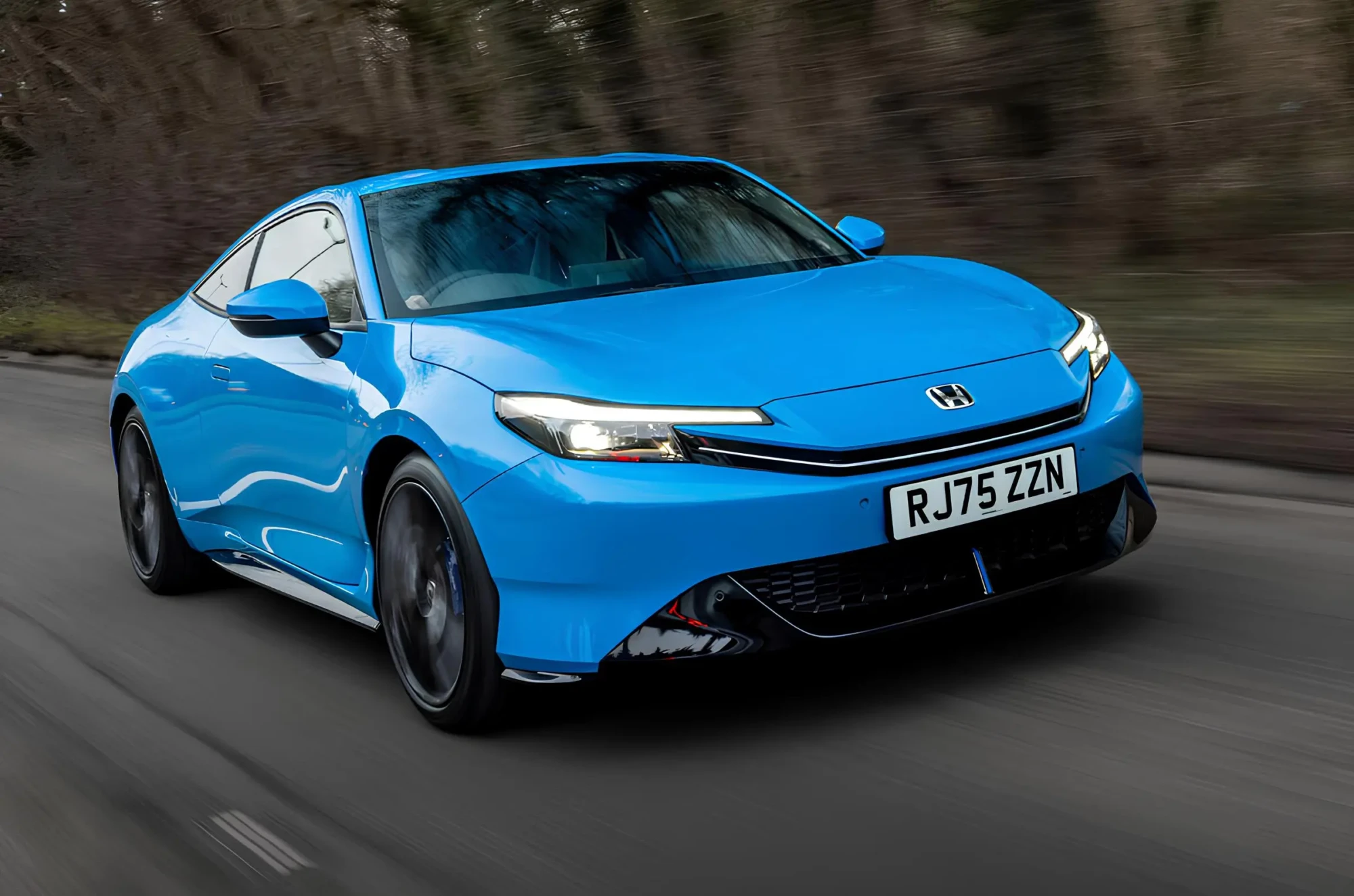 Синє купе Honda у русі на дорозі, вигляд спереду збоку