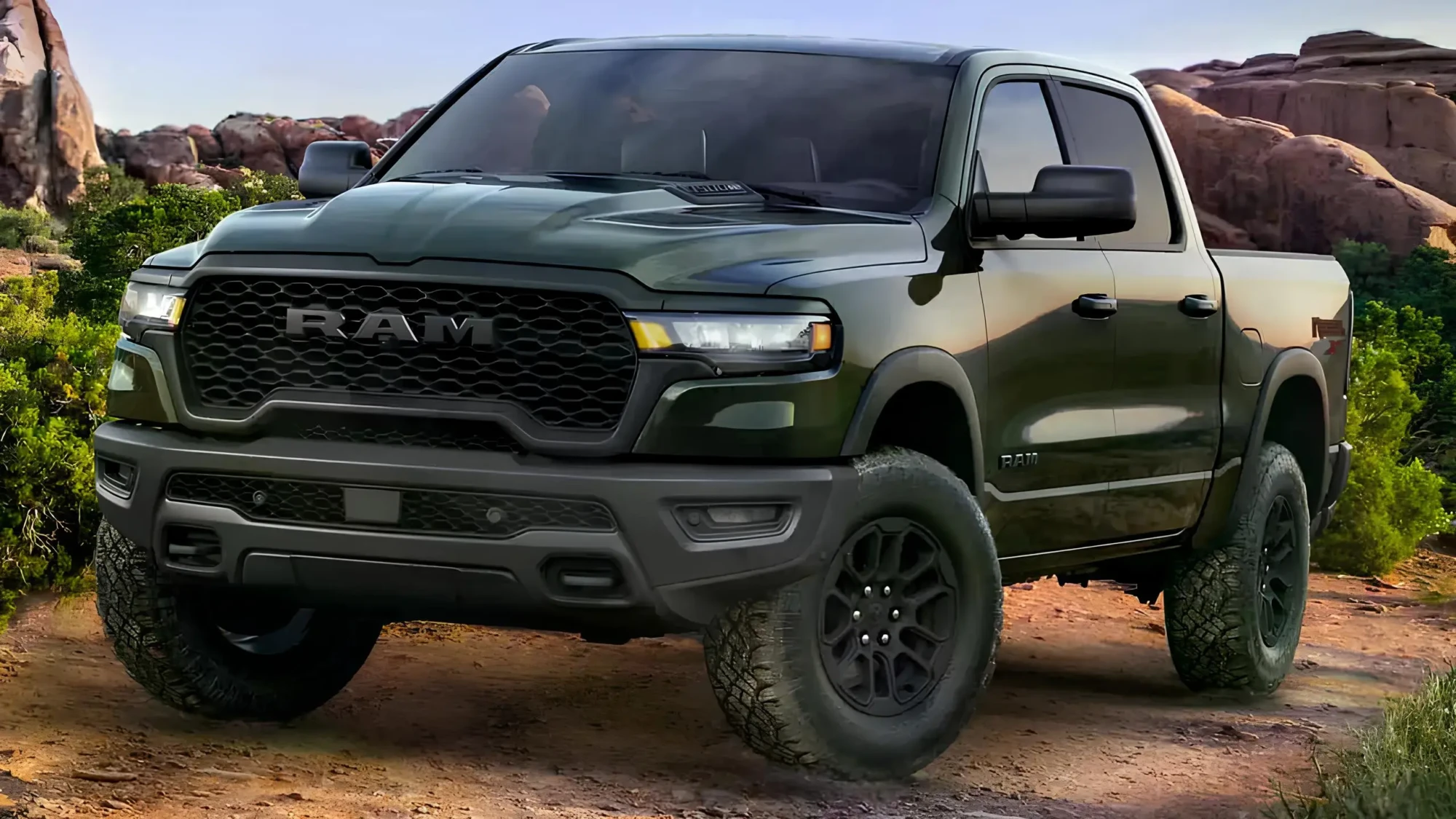 Темно-зелений пікап RAM на позашляхових шинах стоїть на ґрунтовій дорозі серед скель і кущів у каньйоні, вид спереду під кутом.