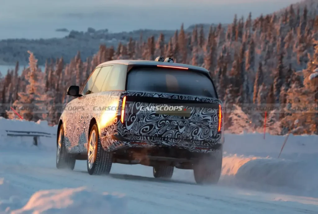 Замаскований прототип великого SUV на зимовій дорозі. Вид ззаду. Сніг і тепле вечірнє світло. Водяний знак Carscoops.