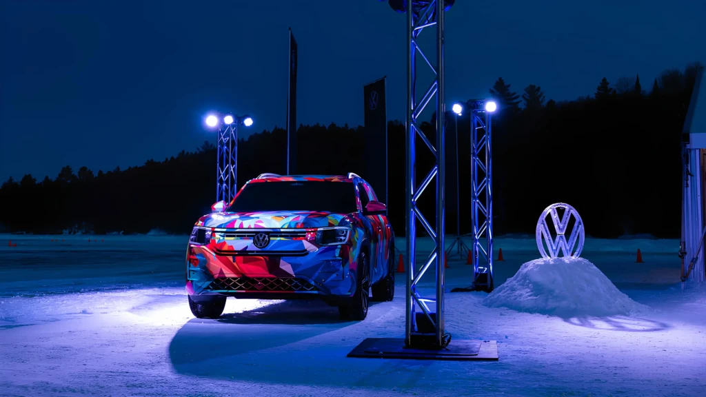 Кросовер Volkswagen у яскравому камуфляжі стоїть на засніженому майданчику вночі під прожекторами.