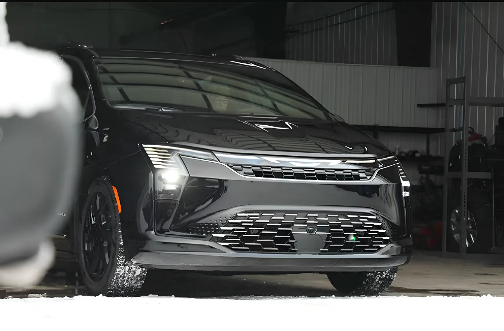 Чорний кросовер у камуфляжі на зимових тестах біля ангару, вигляд спереду збоку