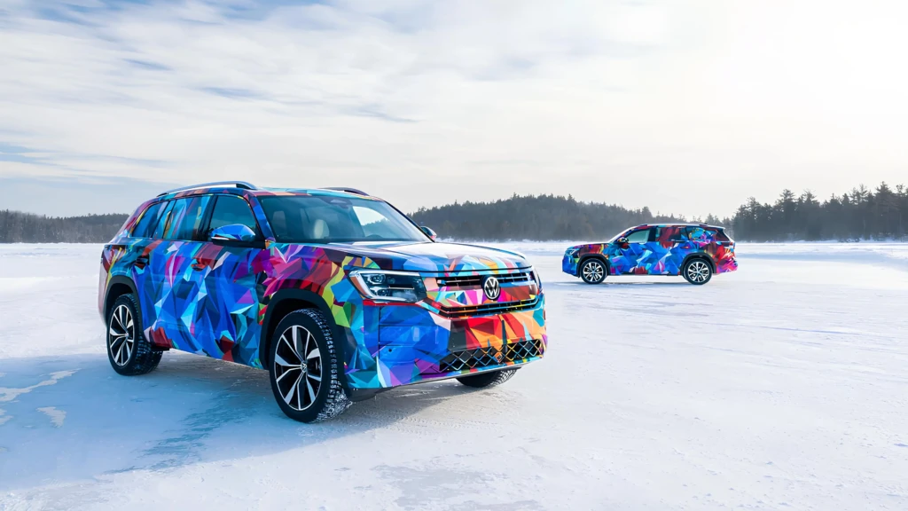 Два кросовери Volkswagen у яскравому камуфляжі стоять на замерзлому озері під час зимових випробувань.