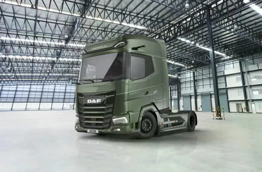 Зелений магістральний тягач DAF XG у великому порожньому ангарі з металевими фермами та панорамними вікнами.