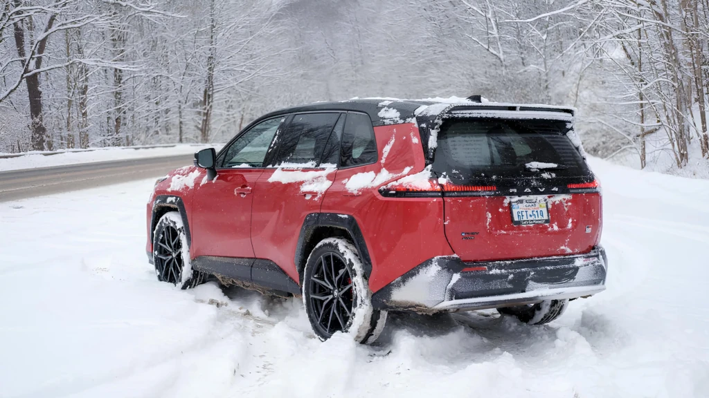 Червоний Toyota RAV4 на снігу: задній ракурс кросовера на зимовій дорозі біля лісу