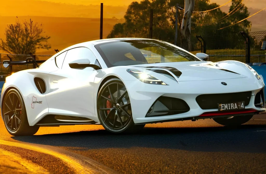 Білий спорткар Lotus Emira на дорозі під час заходу сонця, вигляд спереду збоку