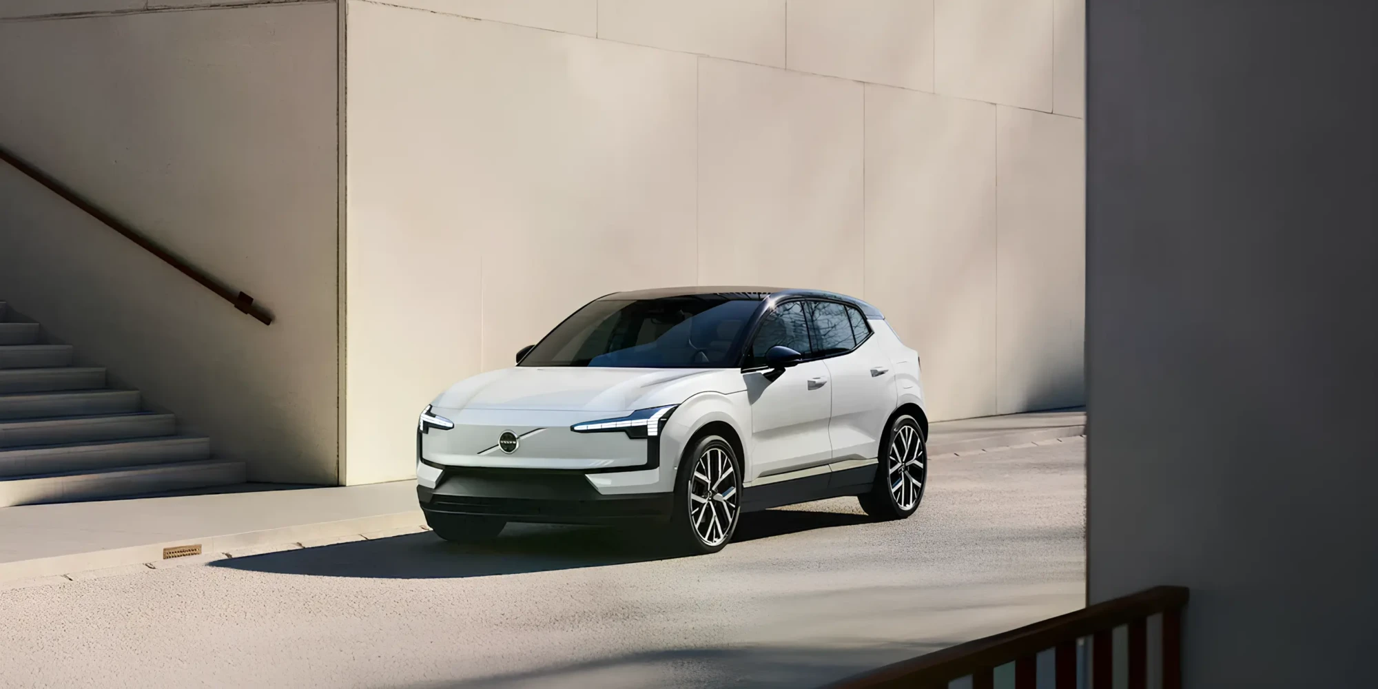 Білий електричний кросовер Volvo в міському середовищі біля будівлі, вигляд спереду збоку