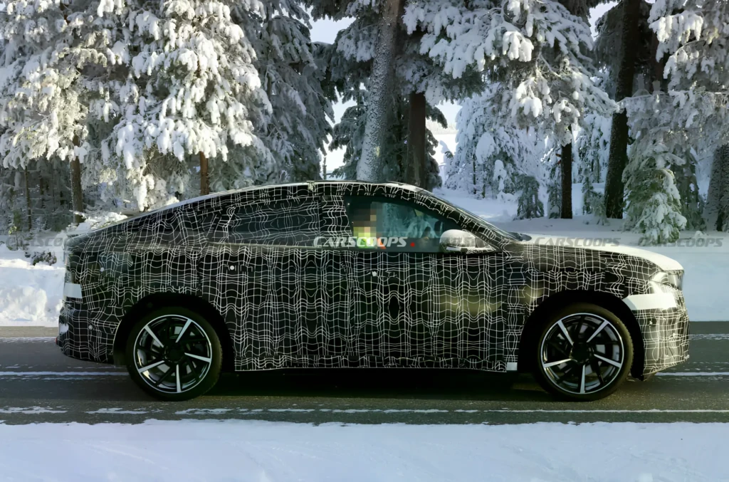 Замаскований прототип BMW iX4 2027 на зимових тестах, профільний вигляд збоку на тлі засніженого лісу