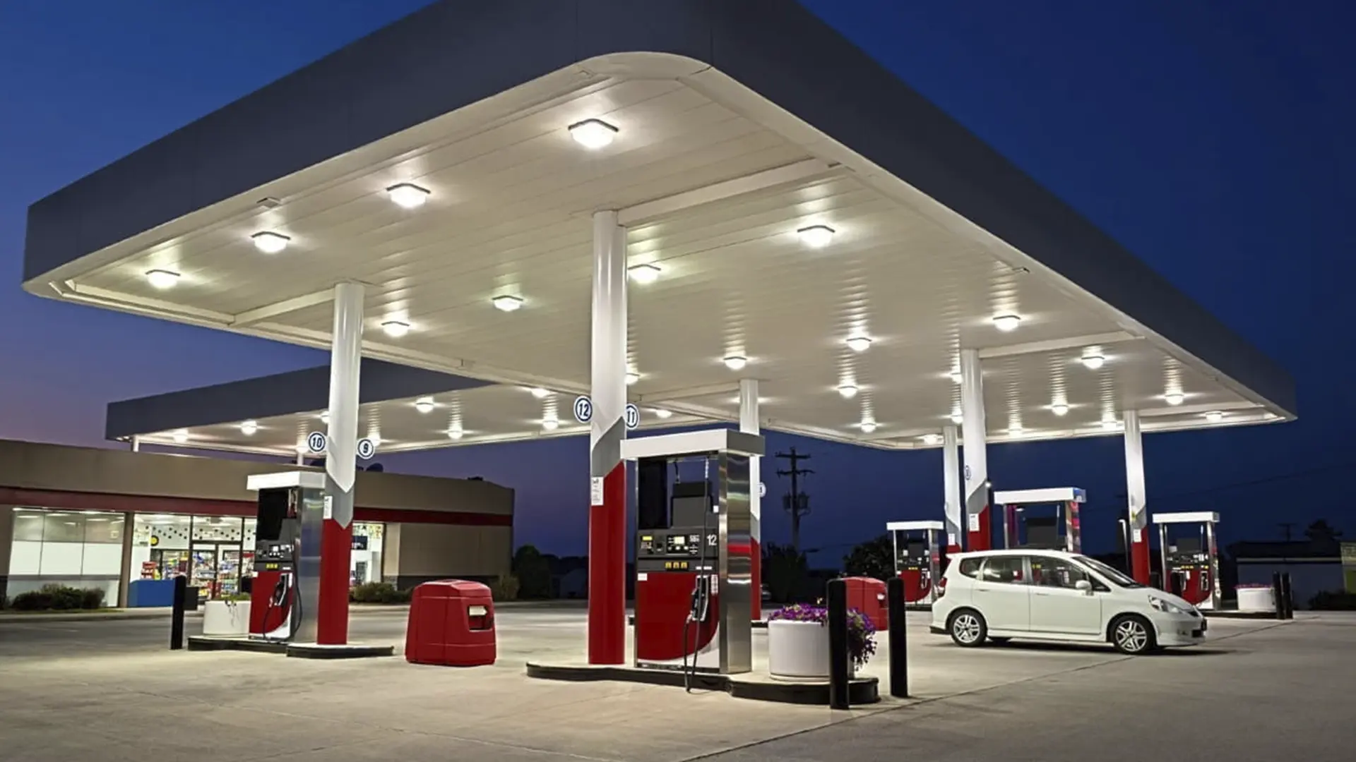 Автозаправна станція у вечірній час з паливними колонками та автомобілем
