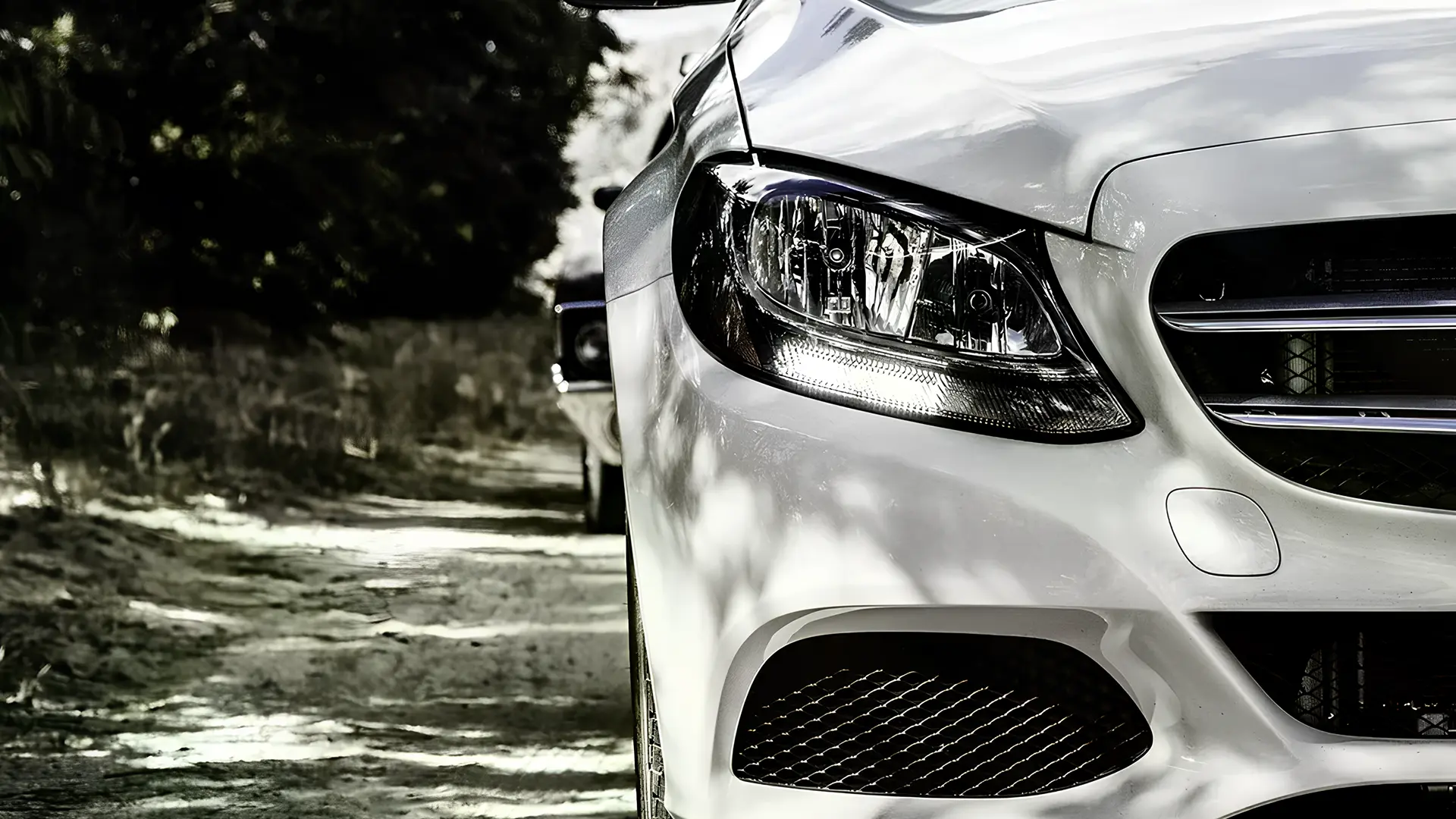 Передня частина білого легкового автомобіля крупним планом, фара та решітка радіатора