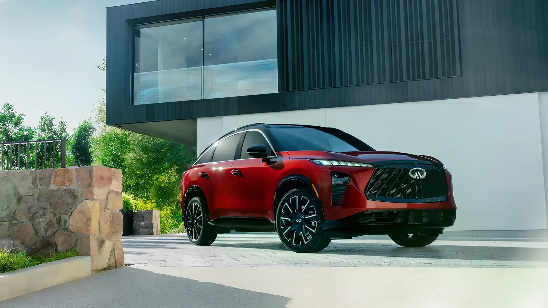Infiniti QX65 червоного кольору біля сучасного будинку, вид спереду збоку