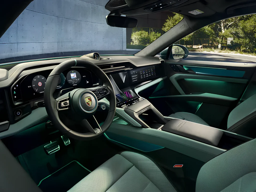 Интерьер Porsche: руль с эмблемой, цифровая приборная панель и широкий дисплей мультимедиа с бирюзовой подсветкой салона