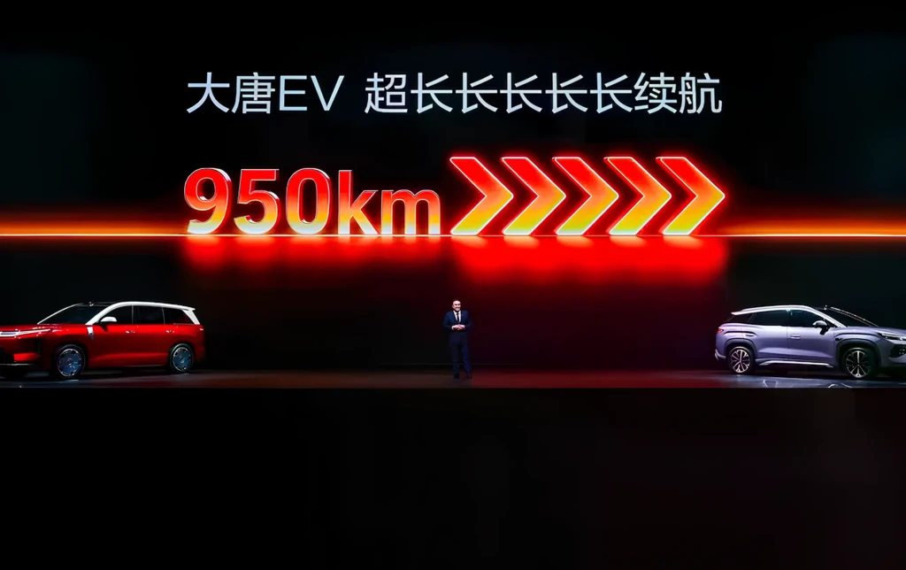 Слайд презентації про електромобіль: напис 950 км запасу ходу та китайський текст, по боках два авто на сцені