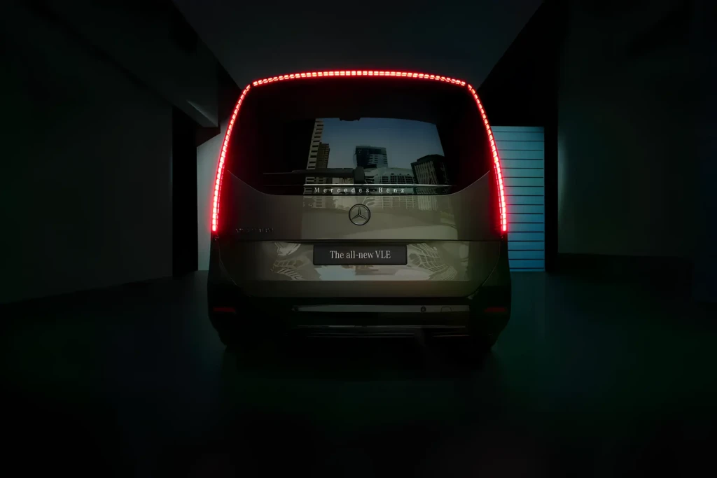 Задній вигляд Mercedes-Benz VLE у темному шоурумі: вертикальні світлодіодні ліхтарі по краях та суцільна червона світлова лінія зверху