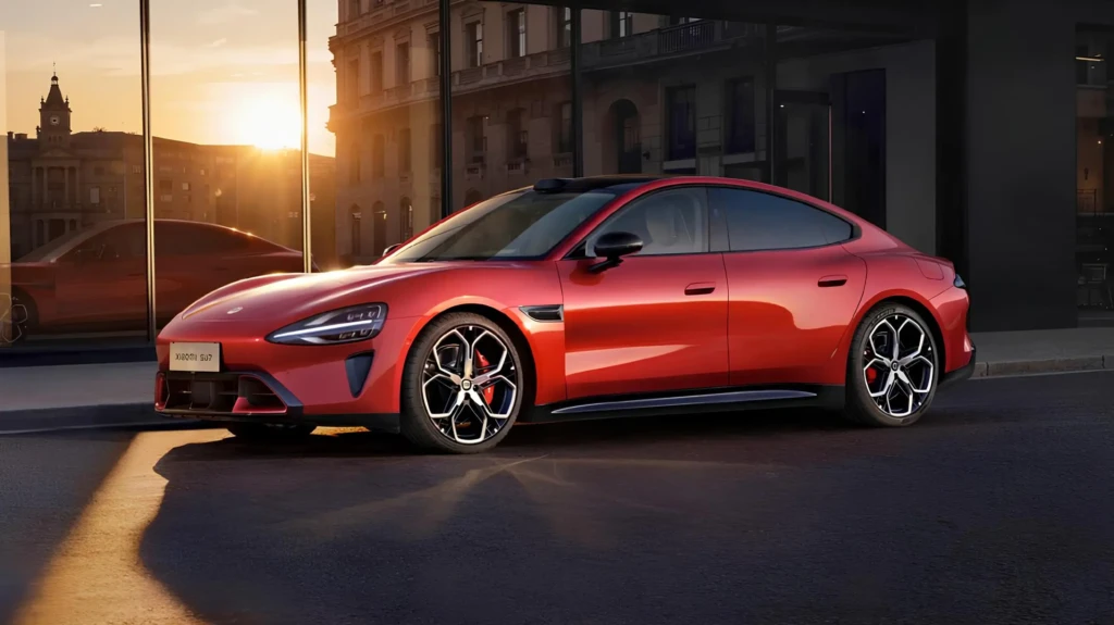 Оновлений Xiaomi SU7 червоного кольору на міській вулиці на заході сонця, вигляд збоку, спортивний силует і великі диски