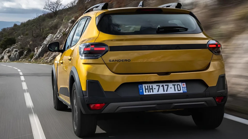 Наступний Dacia Sandero золотистого кольору в русі, вид ззаду збоку