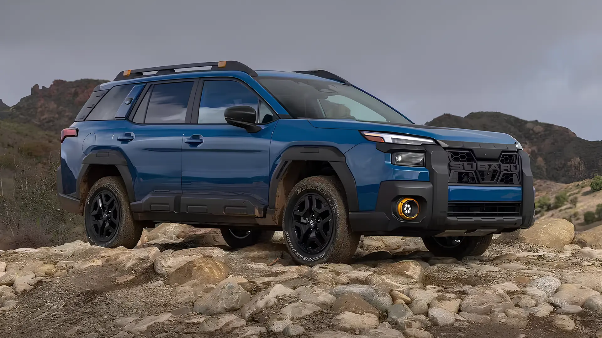 Оновлений Subaru Outback 2026 синього кольору на кам’янистому бездоріжжі, вид спереду збоку