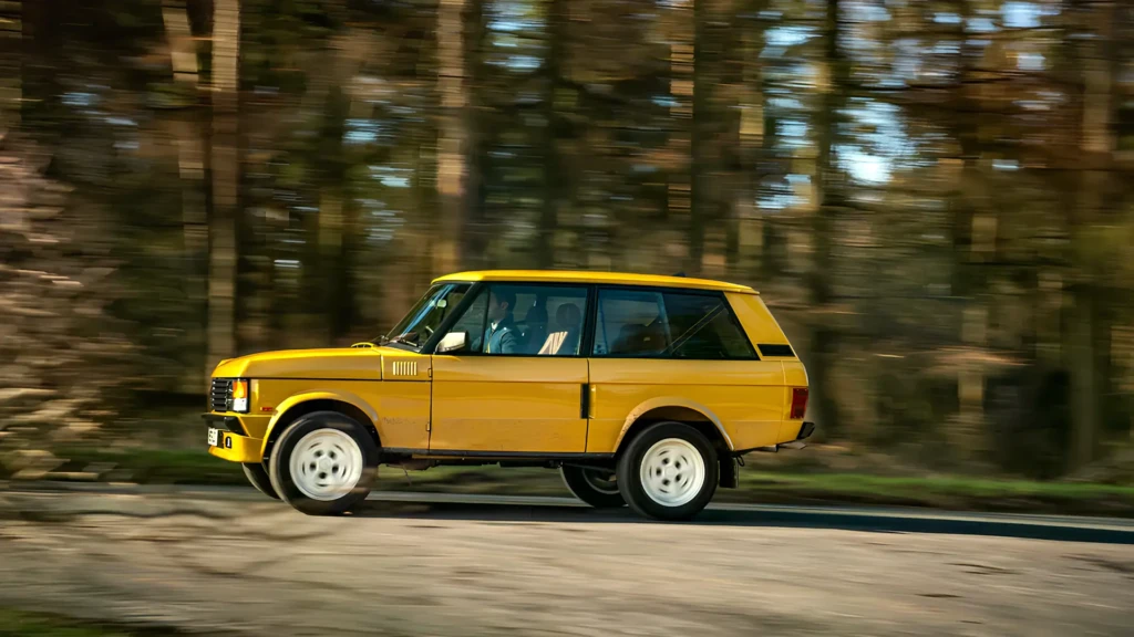 Range Rover Classic жёлтого цвета в движении, вид сбоку