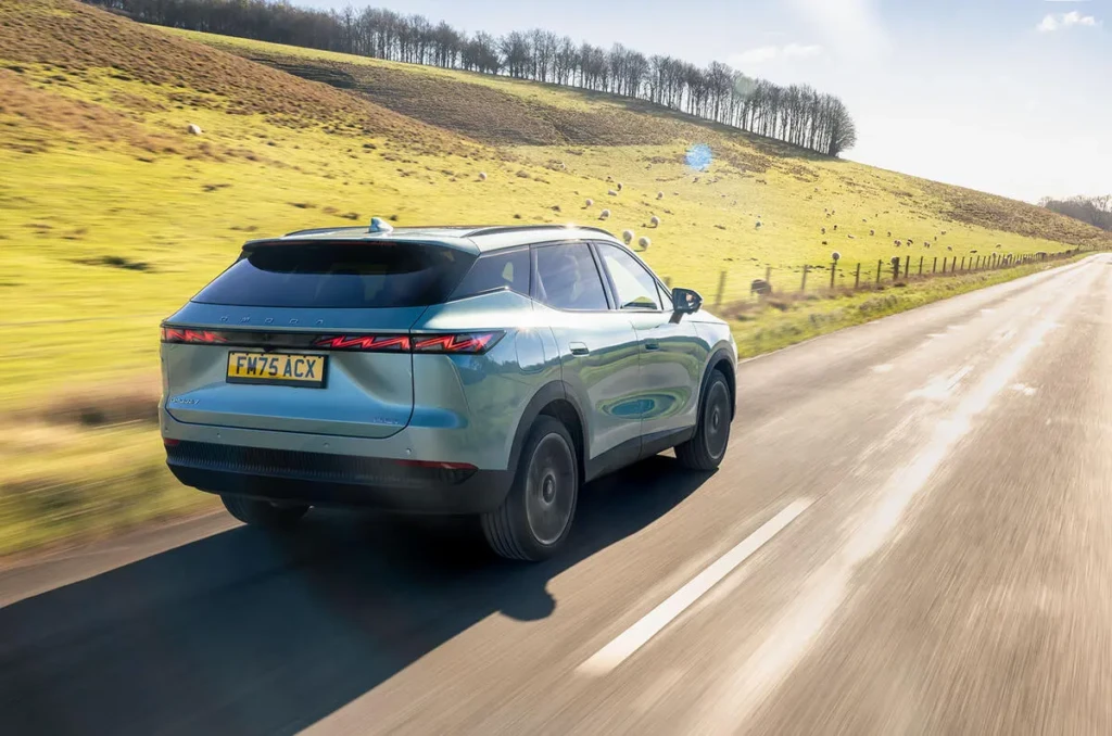 Кросовер Omoda 7 у русі заміською дорогою, вигляд ззаду збоку, світлодіодні задні ліхтарі