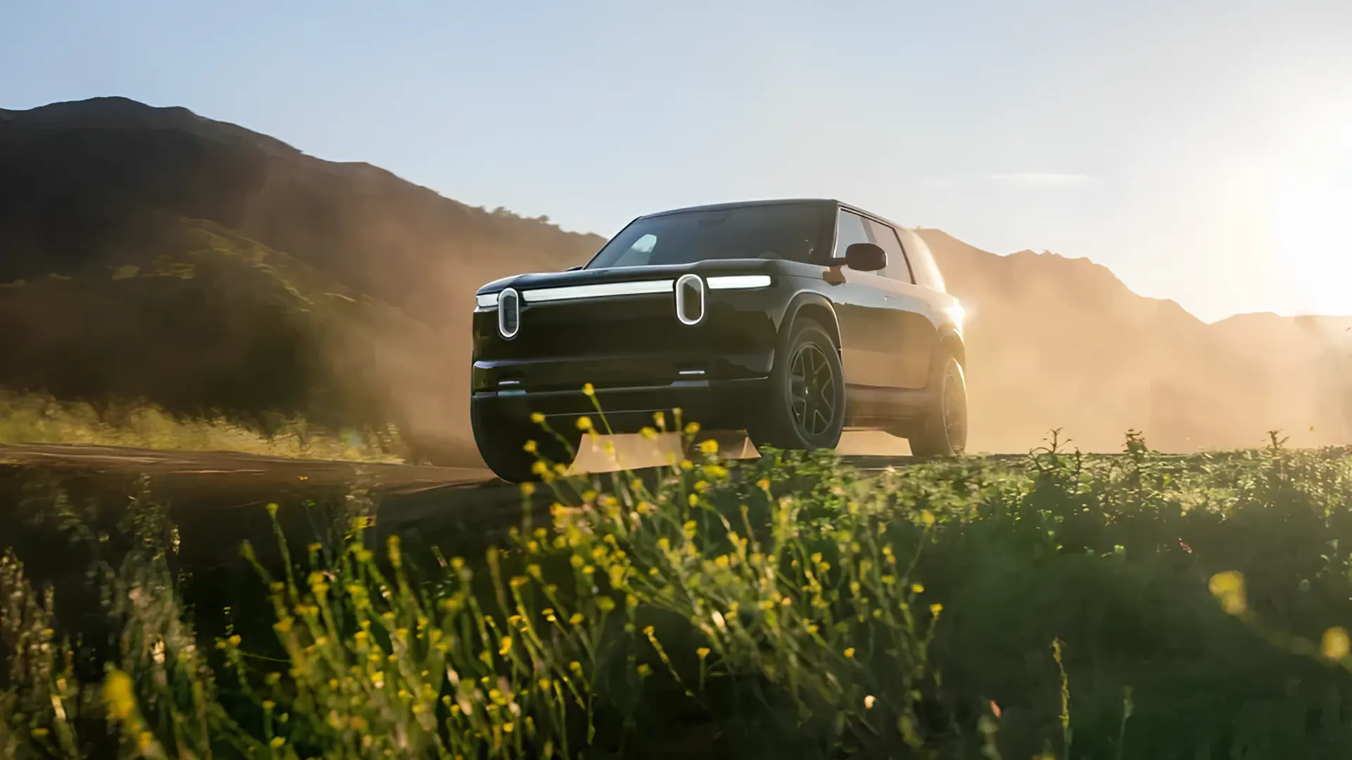 Електричний кросовер Rivian R2 їде ґрунтовою дорогою серед природи