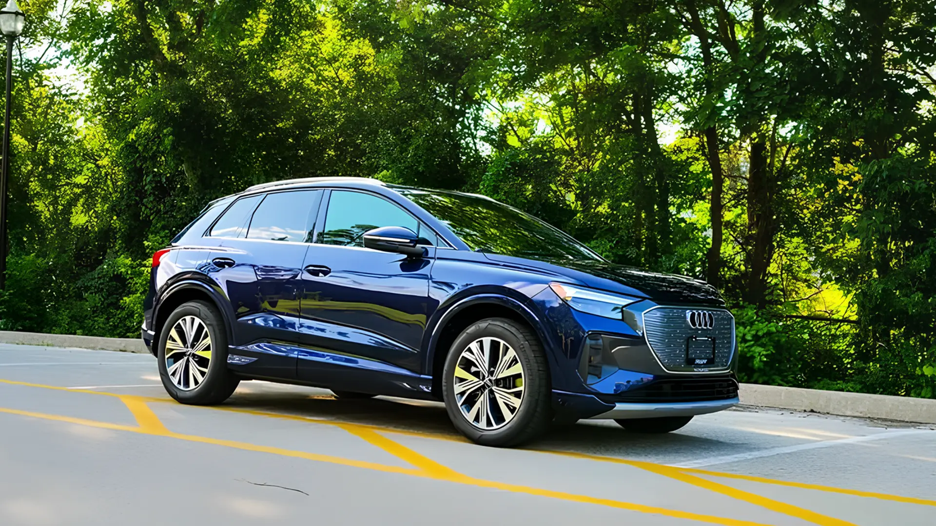 Синій Audi Q4 e-tron припаркований на дорозі біля зелених дерев, вид спереду збоку
