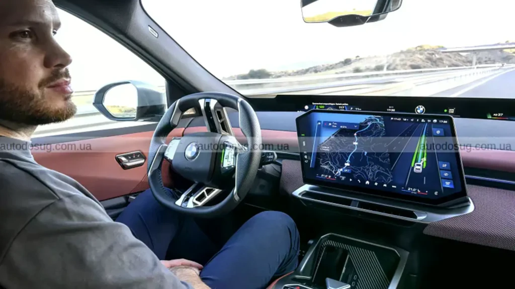 Водій у салоні BMW з цифровою панеллю, навігацією та системами допомоги під час руху