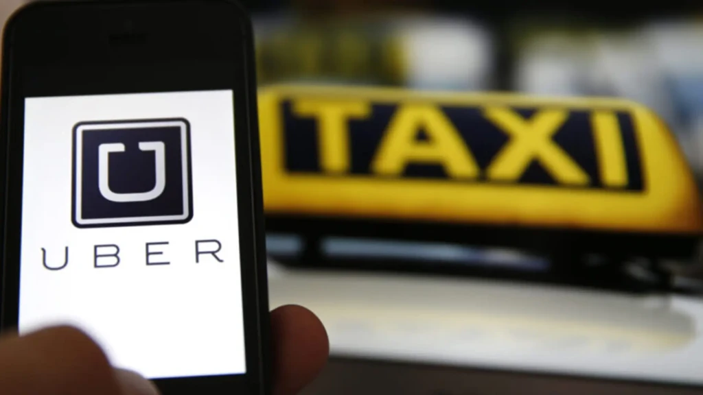 Смартфон із логотипом Uber на тлі таблички таксі як ілюстрація інвестицій компанії у роботаксі