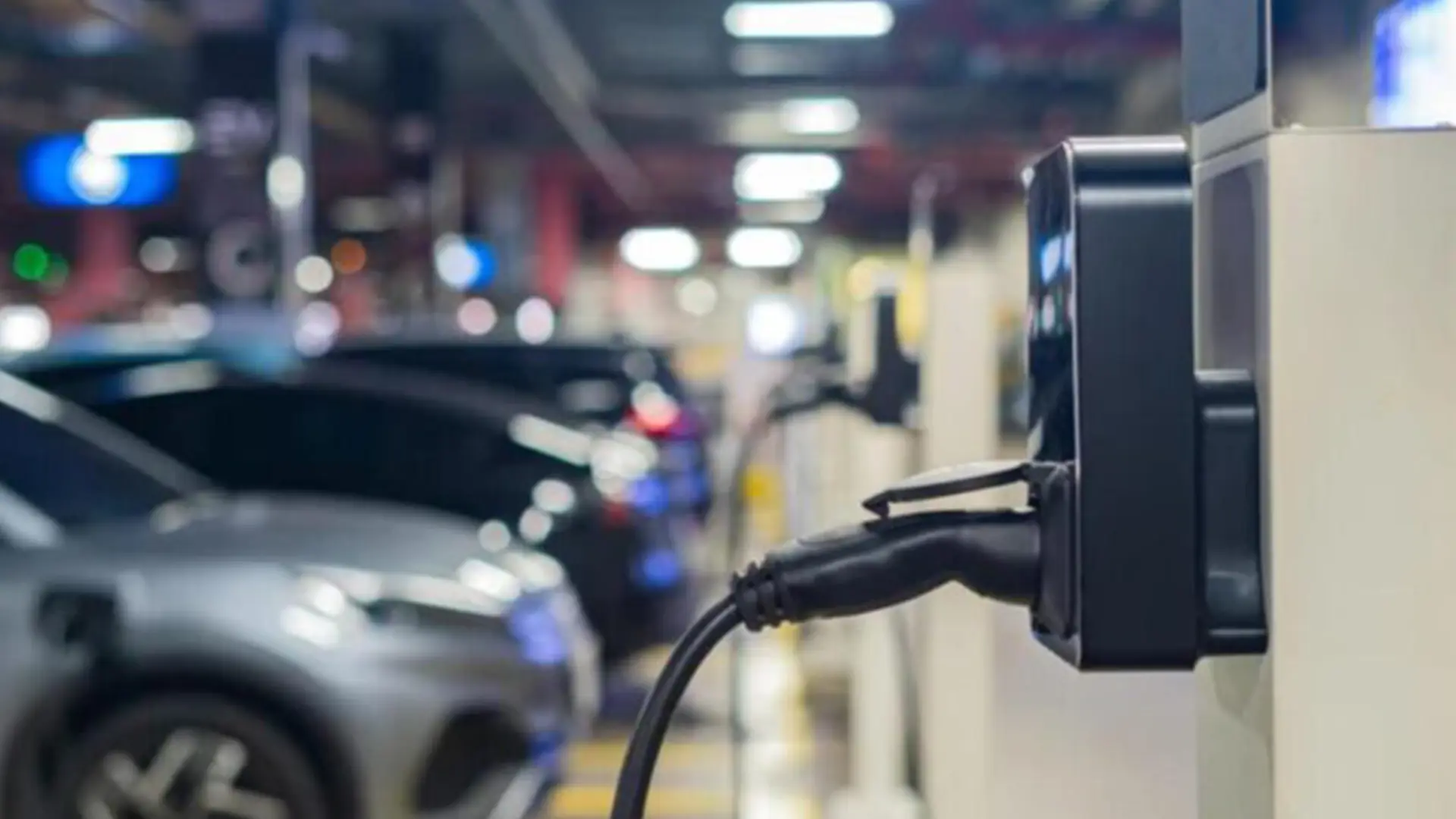 Зарядний кабель підключений до електромобіля на зарядній станції як ілюстрація реального запасу ходу електрокарів