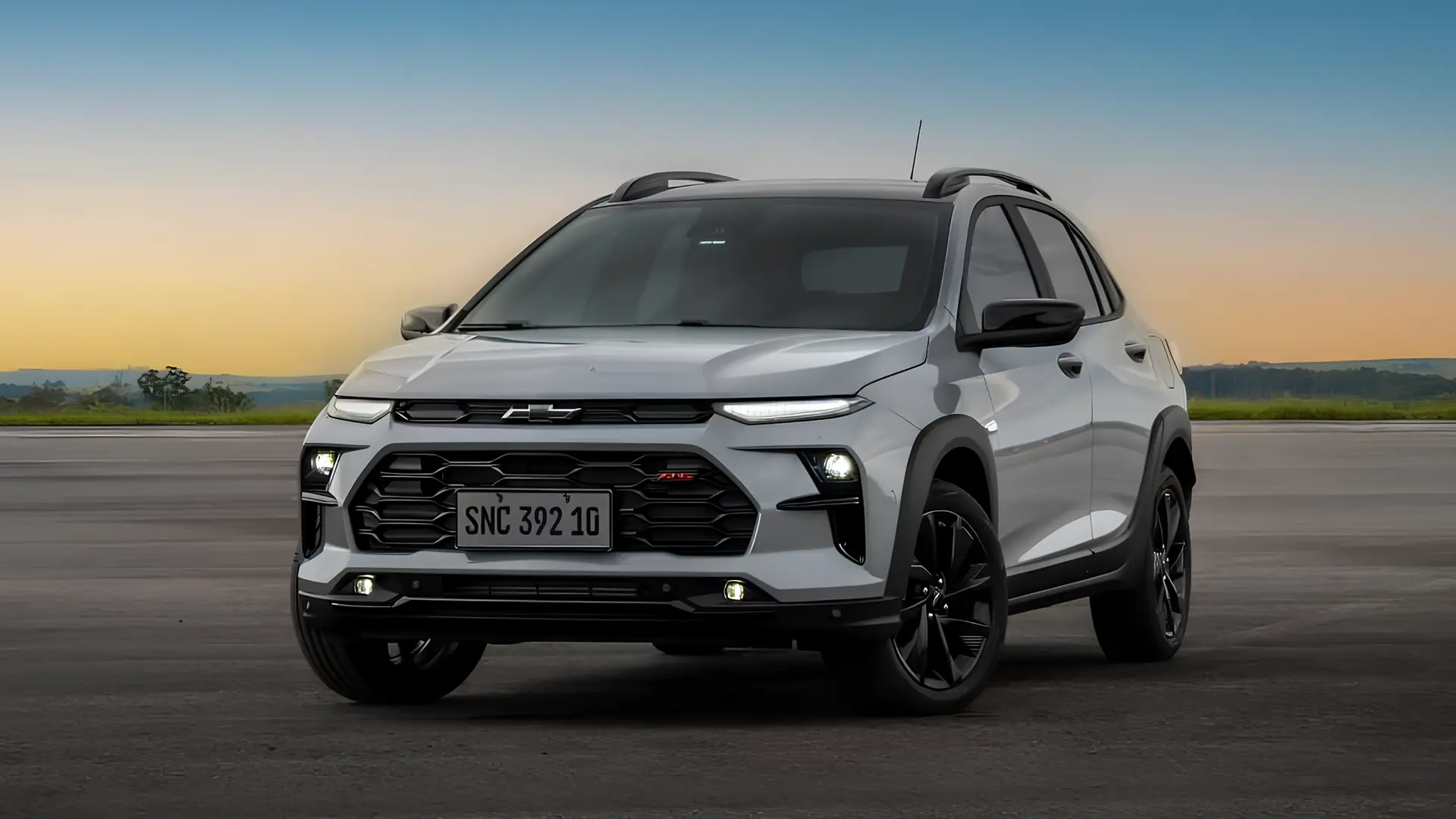 Білий кросовер Chevrolet Sonic на асфальтованому майданчику на тлі вечірнього неба