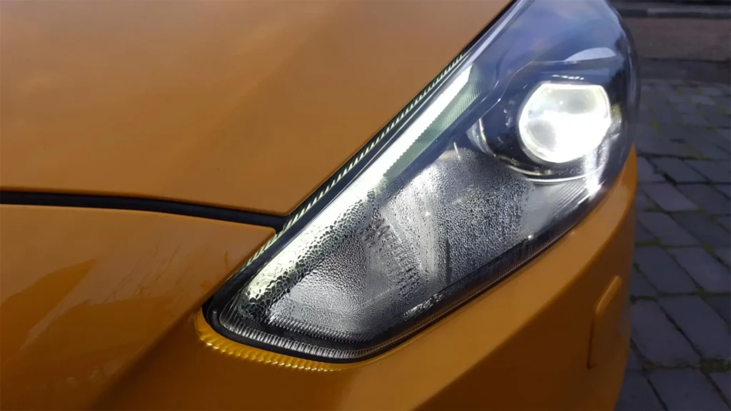 Конденсат у передній фарі автомобіля крупним планом на жовтому кузові