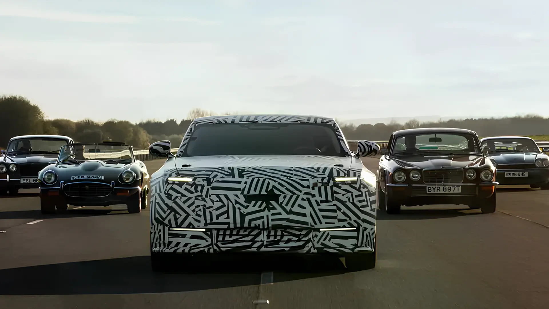 Камуфльований новий Jaguar на трасі поруч із класичними автомобілями як ілюстрація до амбіцій бренду конкурувати з Bentley