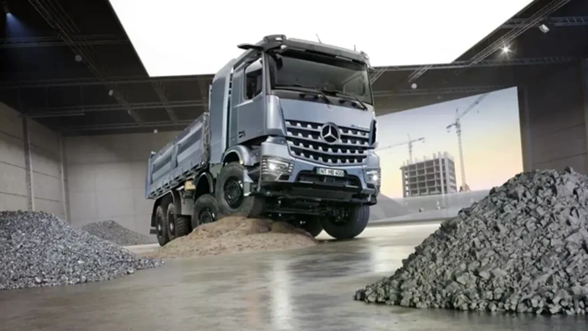 Вантажівка Mercedes-Benz eArocs 400 на будівельному майданчику з насипами щебеню та піску