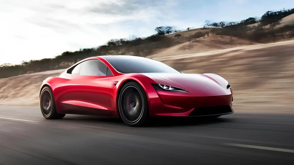 Червоний електричний спорткар Tesla Roadster у русі на дорозі