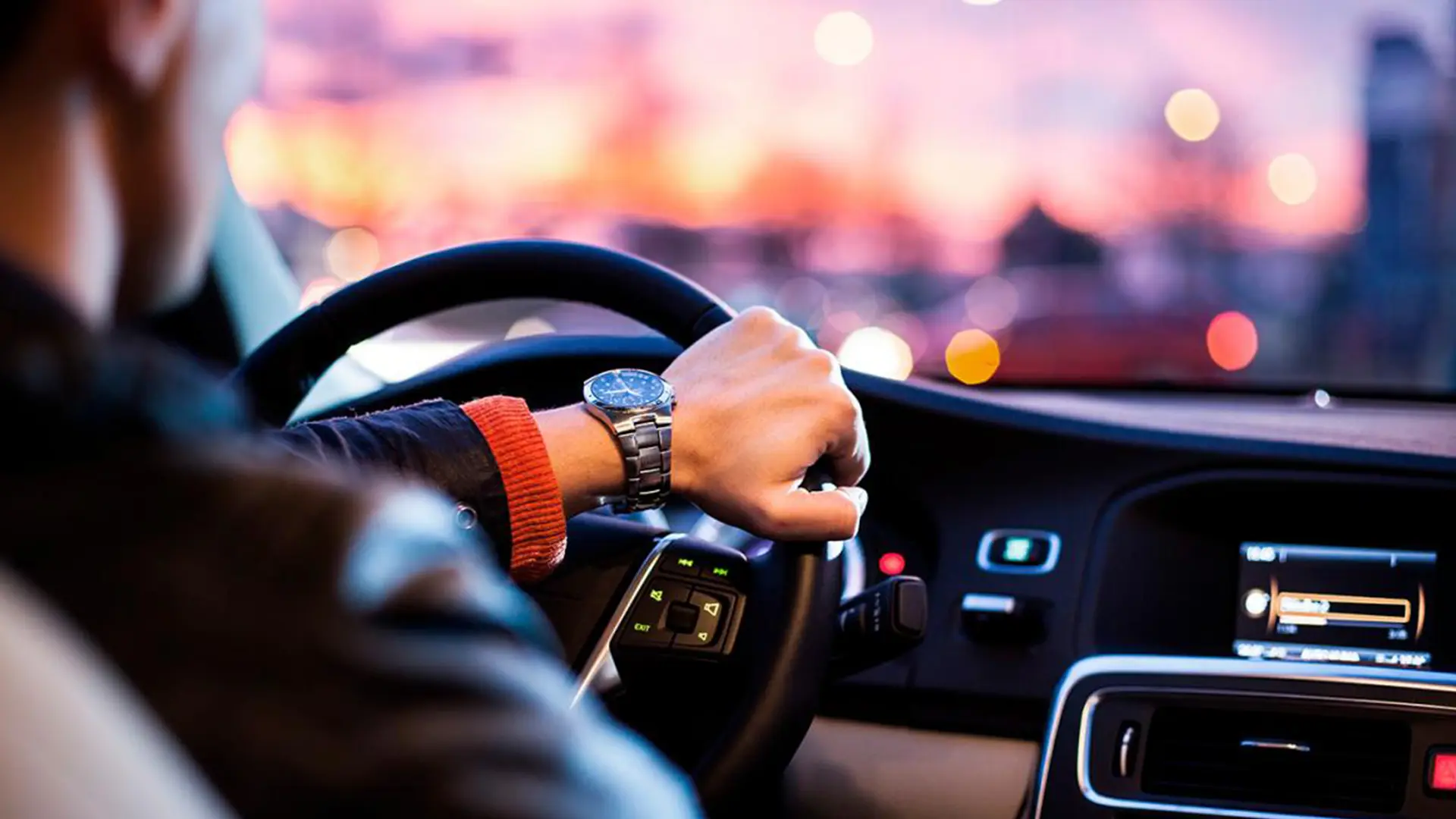 Водій за кермом автомобіля під час поїздки містом у вечірній час