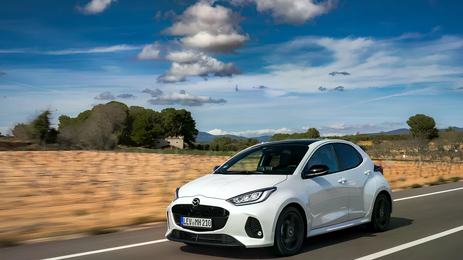 Білий Mazda2 Hybrid 2026 у русі заміською дорогою