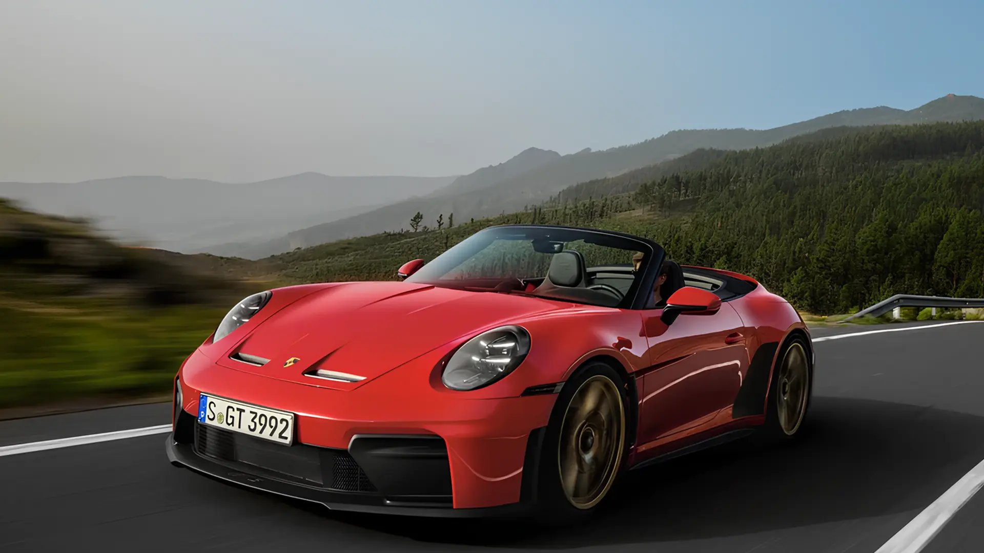 Червоний кабріолет Porsche 911 GT3 у русі гірською дорогою, вид спереду збоку