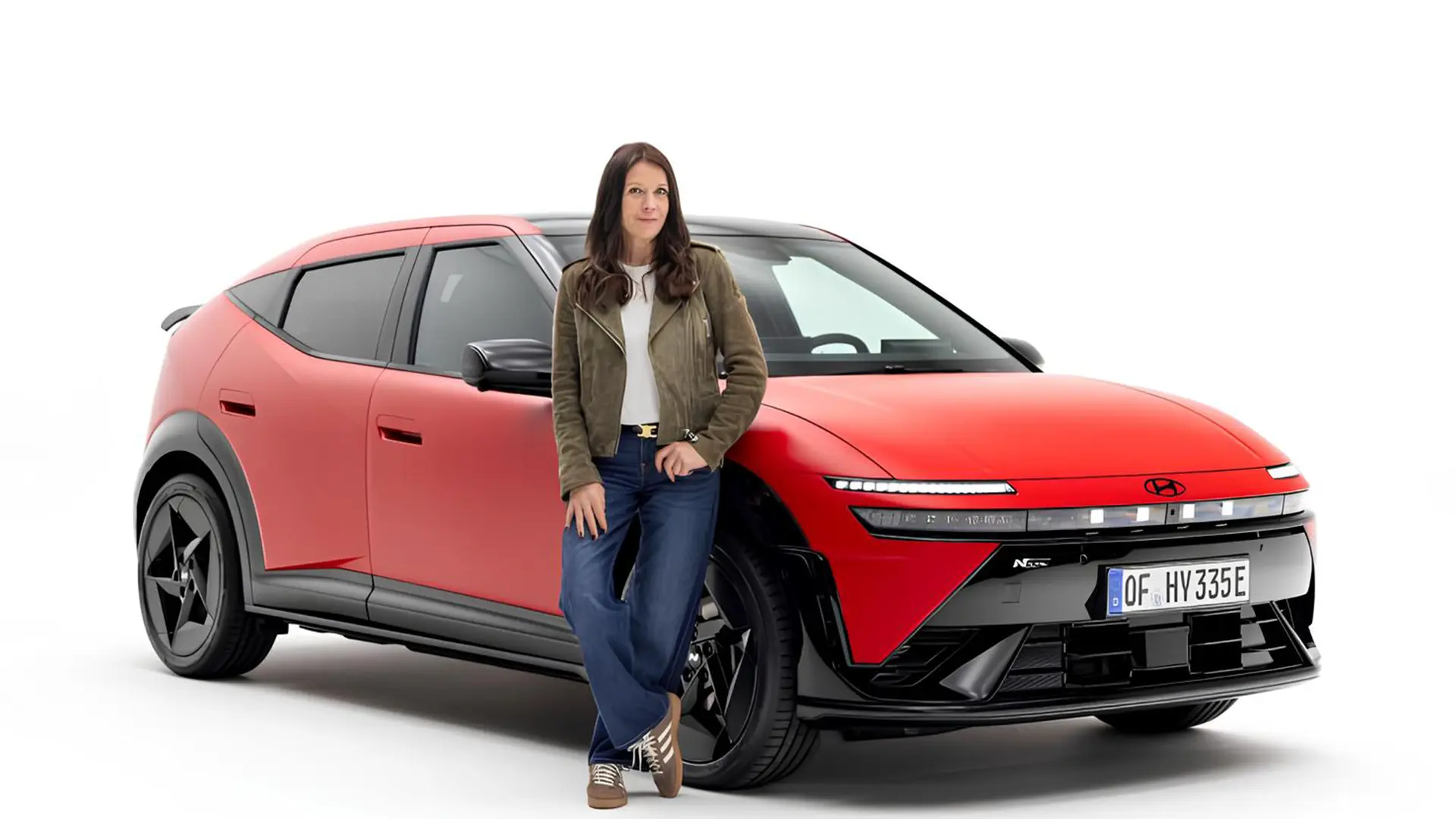 Жінка стоїть біля червоного електромобіля Hyundai Ioniq 3 на студійному фоні