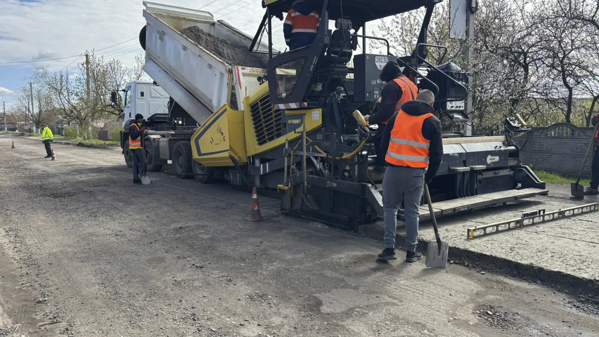 Дорожні працівники укладають асфальт під час ремонту дороги на Харківщині