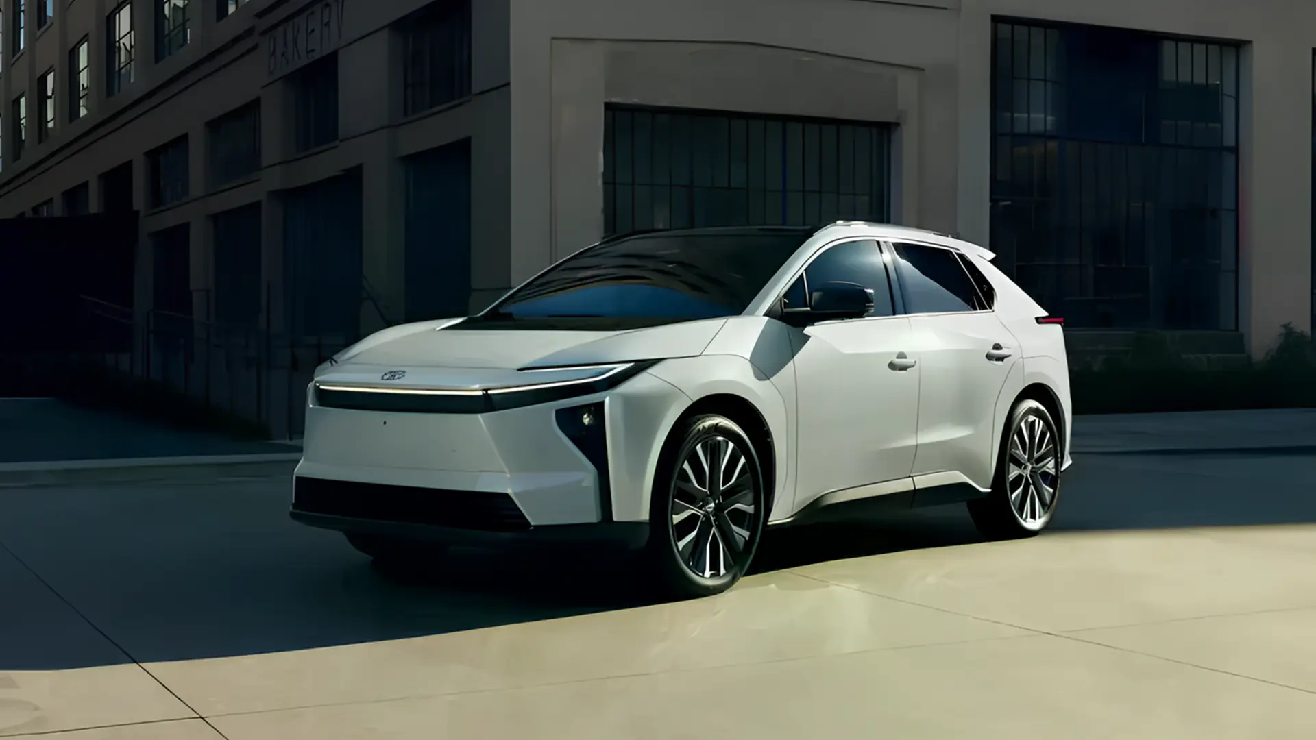 Toyota bZ 2026 білого кольору біля сучасної будівлі