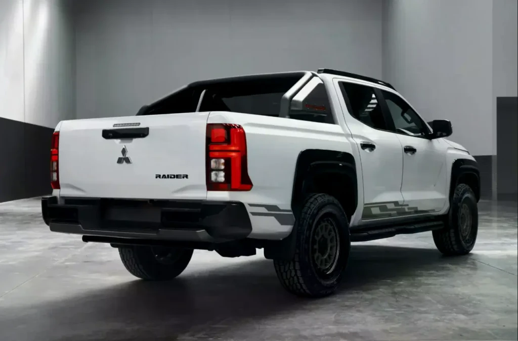 Пікап Mitsubishi Triton Raider білого кольору, вид ззаду збоку в студійному просторі