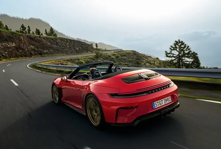 Червоний кабріолет Porsche 911 GT3 у русі гірською дорогою, вид спереду збоку